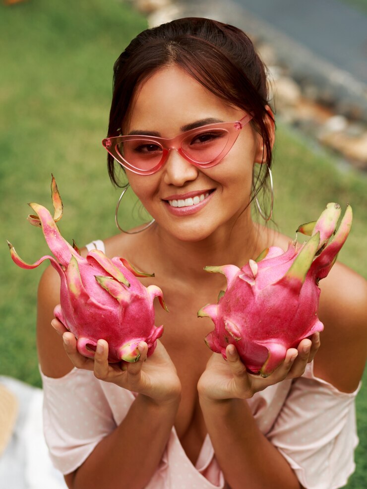 Foto grátis bonita mulher asiática segurando frutas dragão-de-rosa nas mãos
