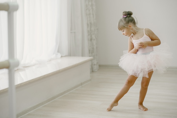 Foto grátis bonitinhas bailarinas em traje de balé rosa. criança com sapatilhas de ponta está dançando na sala. criança na aula de dança.