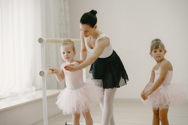 Bonitinhas bailarinas em traje de balé rosa. Crianças em sapatilhas de ponta estão dançando na sala. Garoto na aula de dança com o professor.