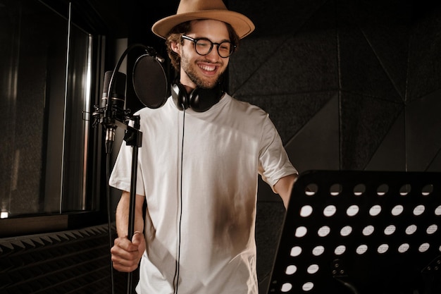 Bonito cantor masculino alegremente gravando nova música no estúdio de som moderno