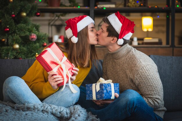Bonito casal de Natal segurando presentes beijando