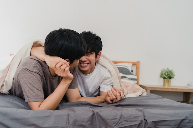 Bonito casal gay asiático falando na cama em casa. jovem asiático lgbtq + cara feliz relaxar descansar juntos passar um tempo romântico depois de acordar no quarto na casa moderna de manhã.
