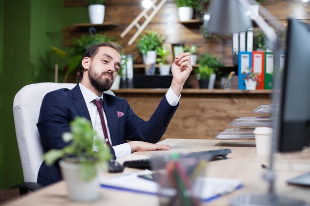 Bonito empresário barbudo olhando orgulhoso no monitor do computador. Empresário caucasiano satisfeito com seu trabalho.