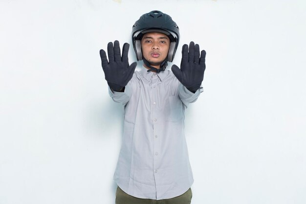 Bonito homem asiático com capacete de motociclista, mão aberta, fazendo sinal de pare com uma expressão séria