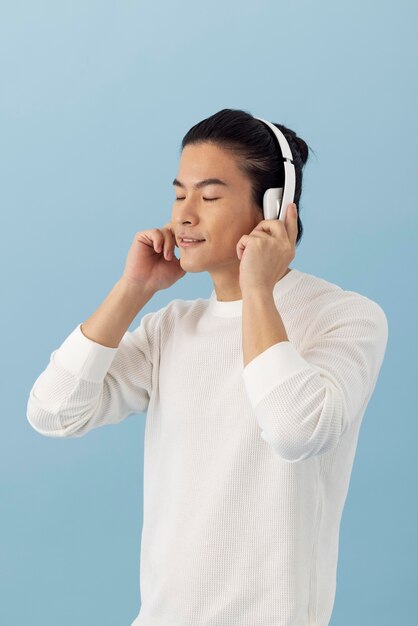 Bonito homem asiático ouvindo música com fones de ouvido