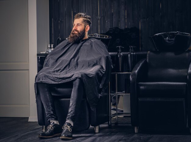 Bonito homem barbudo com antes de lavar o cabelo em um salão de cabeleireiro.