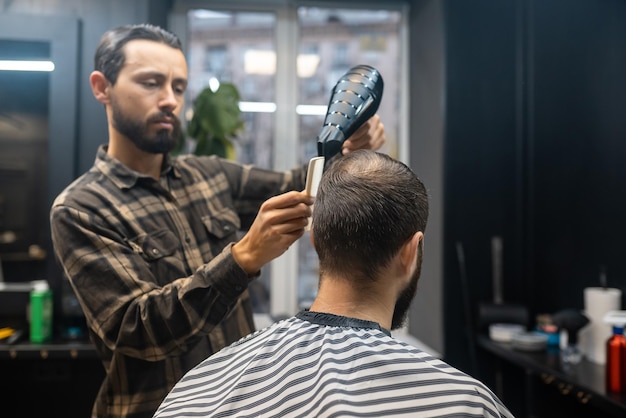 Bonito homem barbudo está recebendo penteado pelo cabeleireiro na barbearia