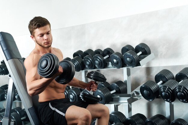 Bonito jovem atleta malhando na Academia