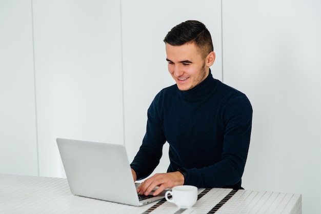 Foto grátis bonito jovem feliz usando um laptop, conversando on-line