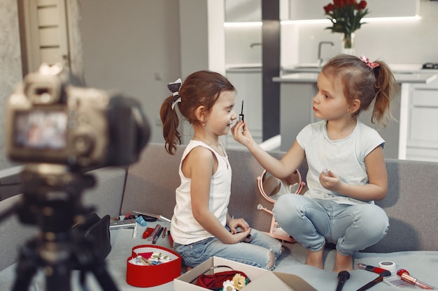 Bonito pequeno blogueiro com cosméticos, gravação de vídeo em casa