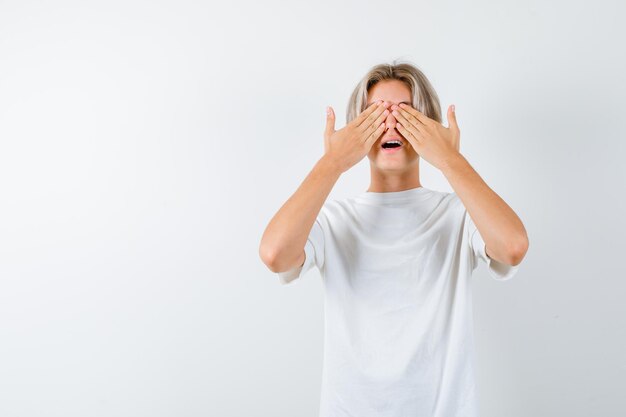 Bonito rapaz adolescente com uma t-shirt branca a cobrir os olhos