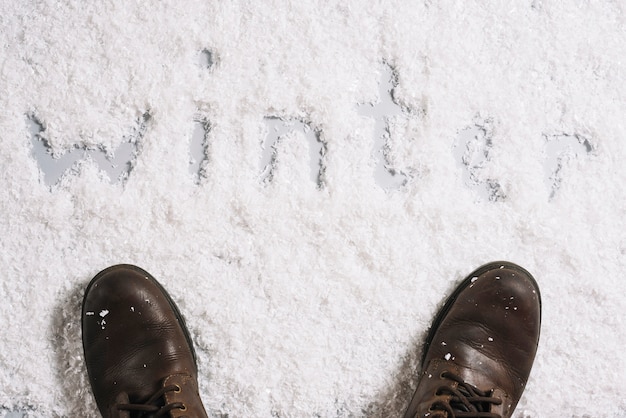 Foto grátis botas perto de título de inverno na superfície de neve