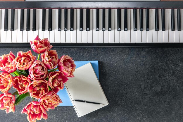 Bouquet de flores e blocos de notas de piano em uma vista superior de fundo escuro