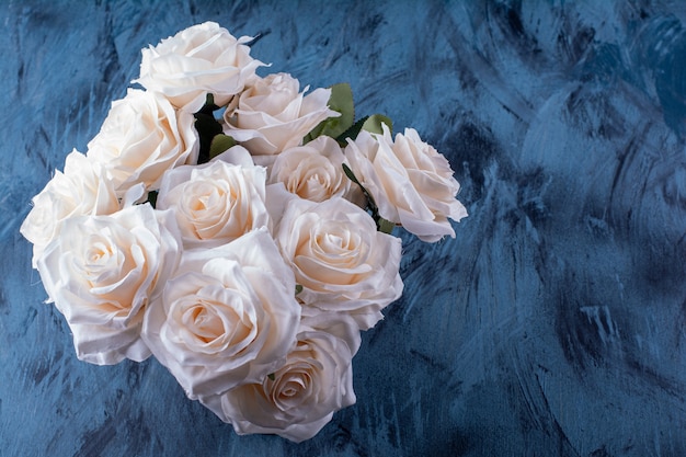 Bouquet de muitas rosas brancas colocadas em azul.