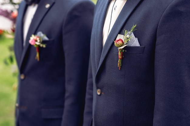 Boutonnieres vermelhos presos aos casacos de groomsmen