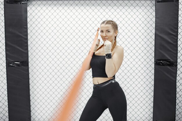 Boxe de mulher. Iniciante em uma academia. Senhora em uma roupa esporte preta.