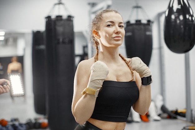 Boxe de mulher. Iniciante em uma academia. Senhora em uma roupa esporte preta.