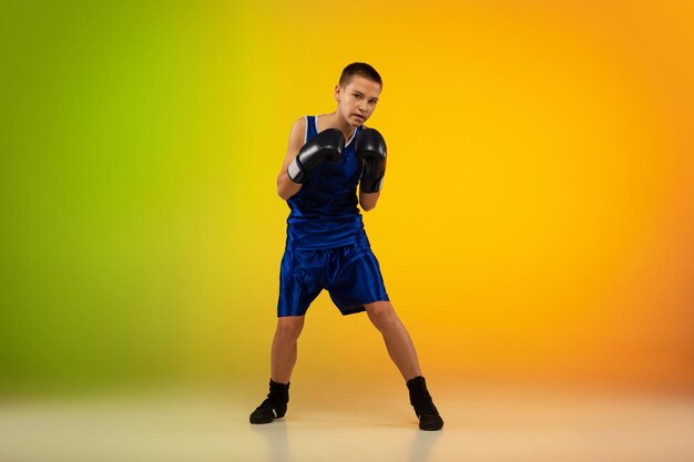 Boxeador adolescente contra estúdio de néon gradiente em movimento de chute, boxe