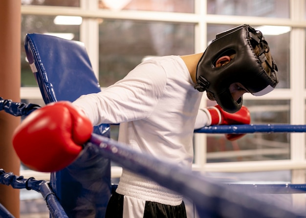 Boxeador masculino com capacete e luvas no ringue