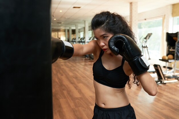 Boxer fêmea treinando no ginásio em luvas de boxe
