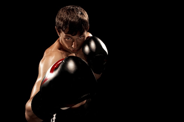 Boxer masculino boxe em saco de pancadas com iluminação nervosa dramática