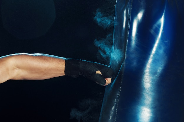 Boxer masculino boxe em saco de pancadas com iluminação nervosa dramática