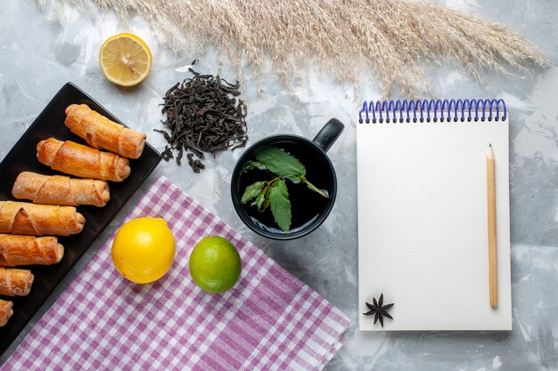 Braceletes doces com vista de cima junto com um bloco de notas de chá de limão na mesa de luz, bolo doce assar chá de açúcar