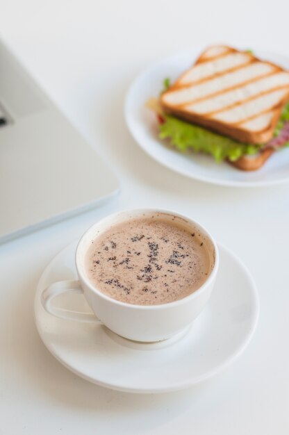 Branca xícara de café com sanduíche no fundo branco