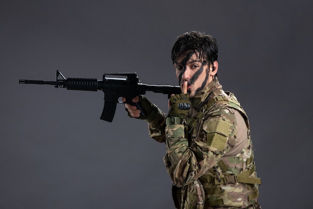 Bravo soldado de frente lutando camuflado com metralhadora na parede escura