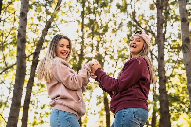 Brincalhão mulheres olhando para a câmera de mãos dadas