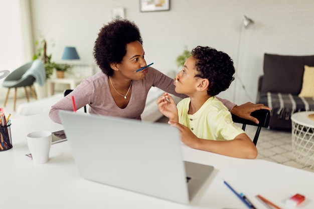 Brincalhão preto mãe e filho se divertindo enquanto homeschooling