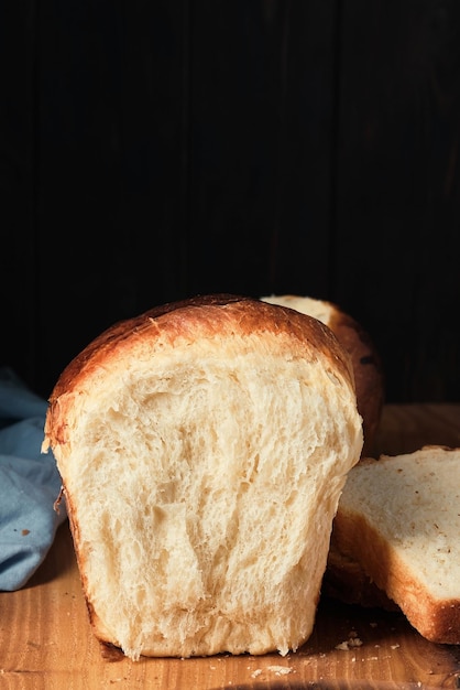 Brioche macio quebrado ao meio em uma placa de madeira Conceito tradicional assado de brioche francês doce Foco seletivo fechado