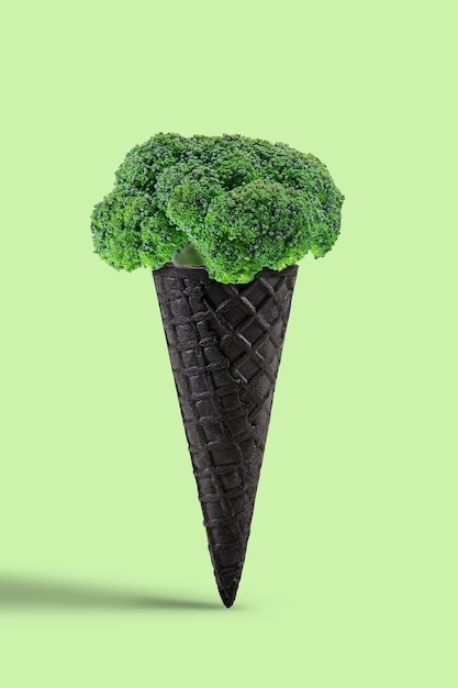 Brócolis maduro em um cone de bolacha preto sobre fundo verde claro. Conceito de nutrição saudável, alimentos e colheita de legumes sazonais. Feche, copie o espaço