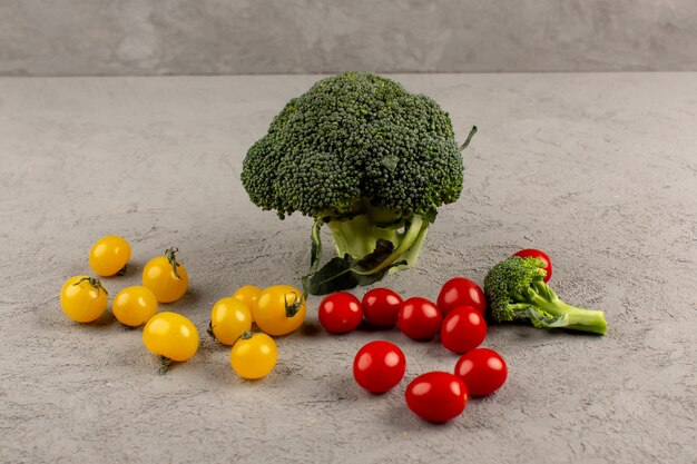 brócolis verde vista superior com tomates amarelos e vermelhos no chão cinza