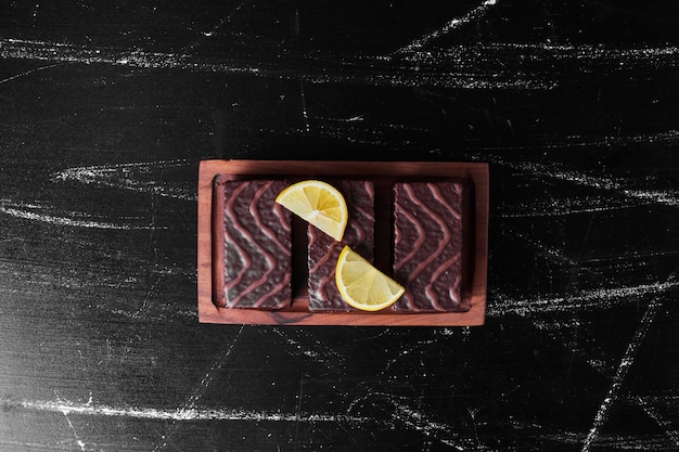 Brownies de chocolate em uma placa de madeira com rodelas de limão.