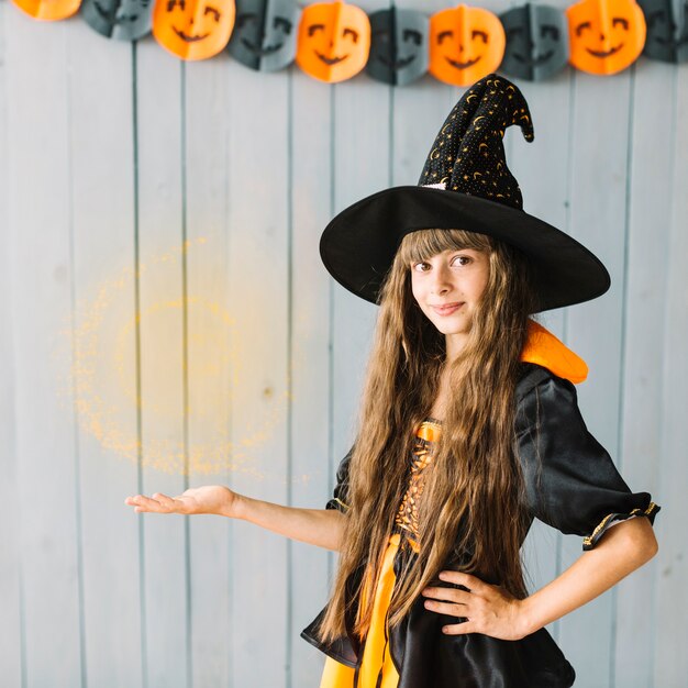 Bruxa jovem mostrando feitiçaria no Halloween