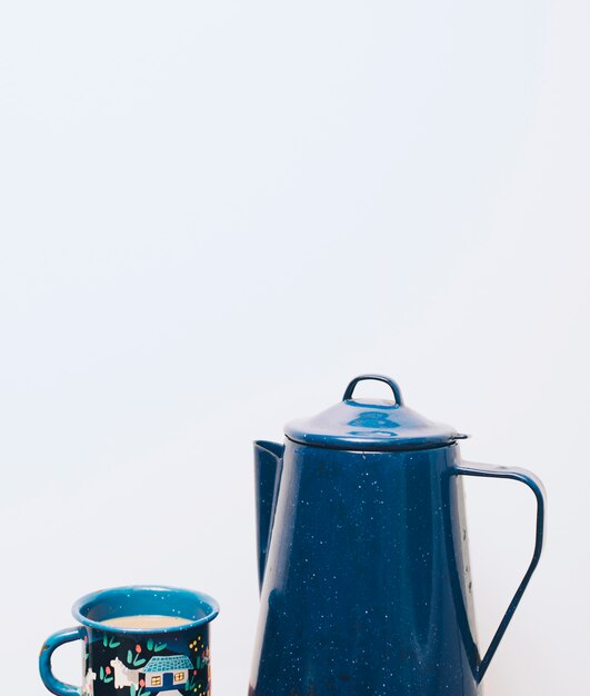 Bule de cerâmica azul e caneca em fundo branco