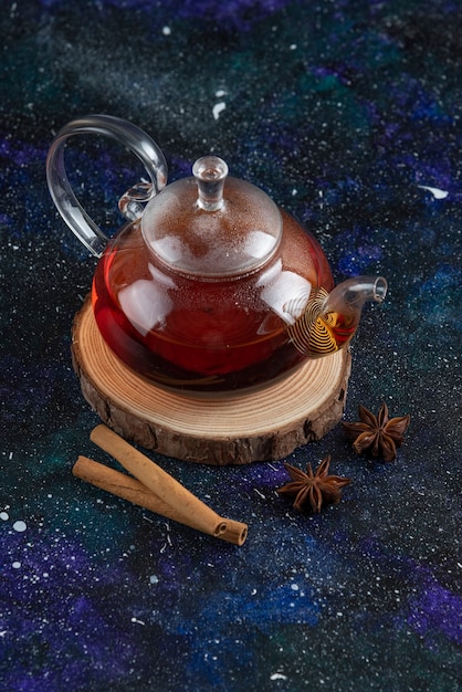 Foto grátis bule de chá de vidro com canela na placa de madeira