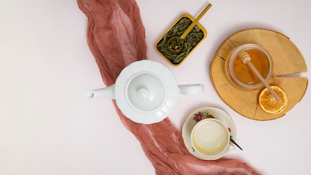 Foto grátis bule de ervas; sai; dipper de mel; citrinos secos; xícara de cerâmica e pires em fundo branco