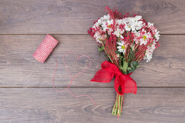 Buquê de flores com coração de corda na mesa