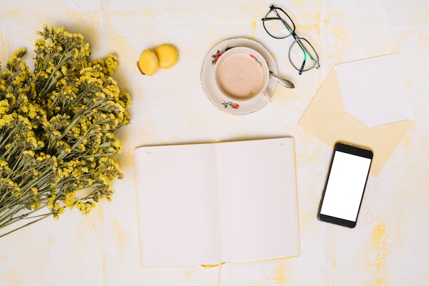 Buquê de flores com smartphone, café e notebook na mesa