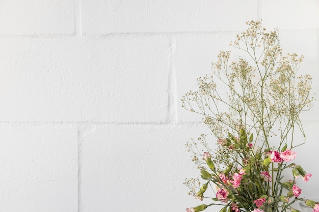 Foto grátis buquê de flores e galhos de plantas perto da parede