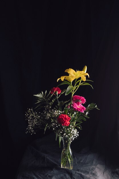 Buquê de flores em vaso em têxtil escuro