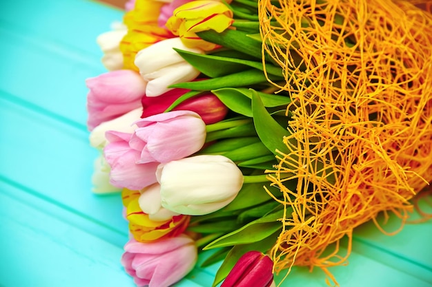 Buquê de flores frescas de tulipas multicoloridas na velha mesa de madeira azul Foto gratuita
