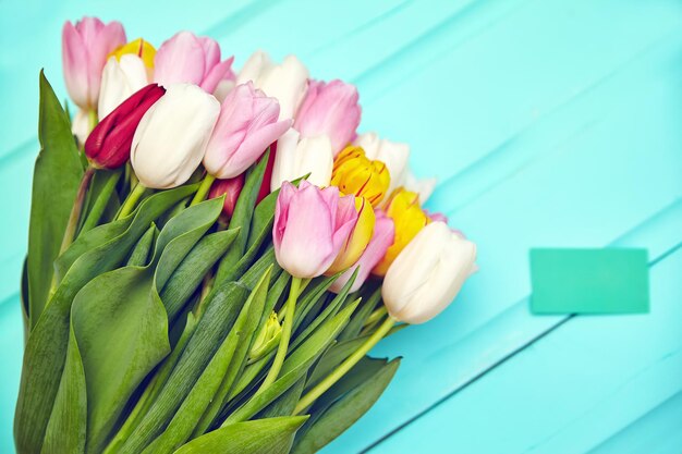 Buquê de flores frescas de tulipas multicoloridas na velha mesa de madeira azul