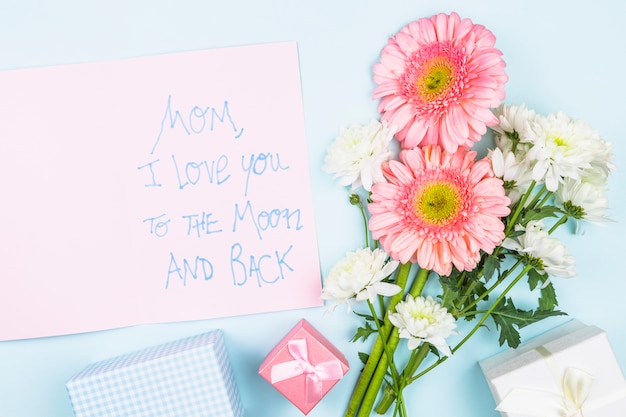 Foto grátis buquê de flores frescas perto de papel com palavras e caixas de presentes