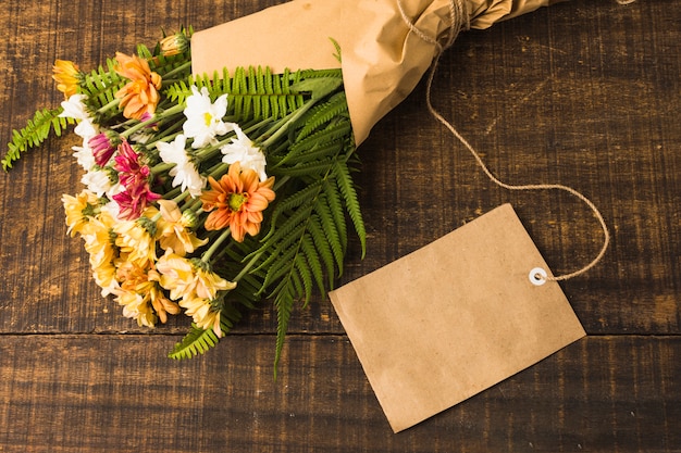 Buquê de flores lindo com rótulo em branco sobre a mesa de madeira