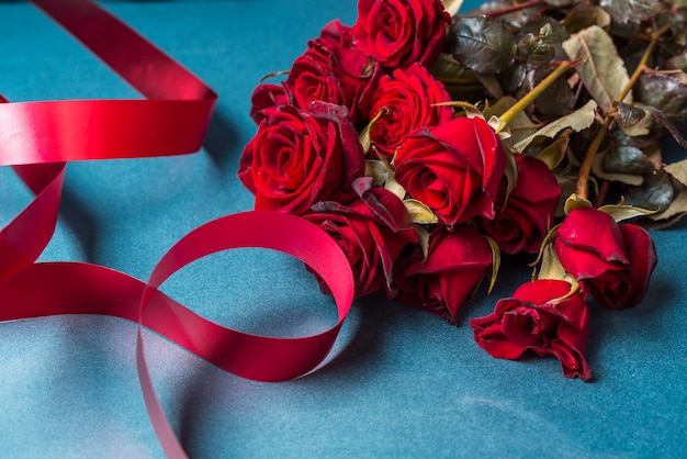 Foto grátis buquê de rosas com fita vermelha na mesa