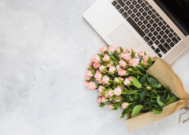 Buquê de rosas com um laptop aberto em fundo de concreto