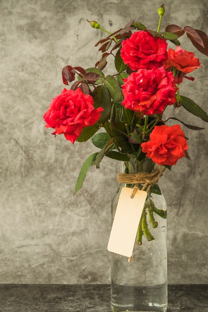 Buquê de rosas vermelhas no frasco de vidro com tag em branco